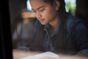 junge Frau, die Buch liest, das drinnen in einem städtischen Café sitzt foto