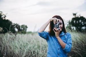 glückliche junge hipster frau mit vintage kamera im feld foto