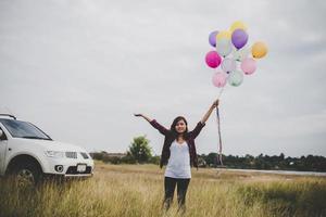 schöne junge Hipsterfrau, die bunte Luftballons draußen hält foto