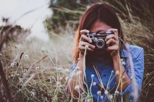 glückliche junge hipster frau mit vintage kamera im feld foto