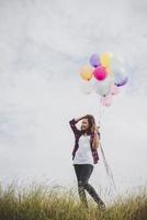 schöne junge Hipsterfrau, die bunte Luftballons draußen hält foto