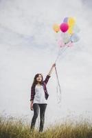 schöne junge Hipsterfrau, die bunte Luftballons draußen hält foto