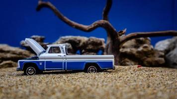 minahasa, indonesien januar 2023, ein spielzeugauto auf dem sand mit einem hintergrund von felsen und blauem himmel foto