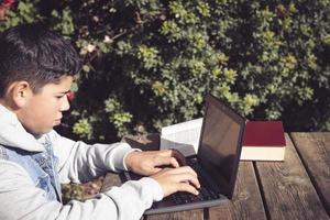 jung Mann schreibt auf ein Laptop, im das Park im das öffnen Luft foto