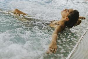 junge Frau, die in der Whirlpool-Badewanne am Pool entspannt foto