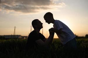 Papa und Sohn halten Hände beim Sonnenuntergang foto