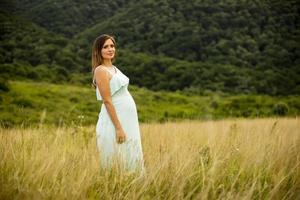 junge schwangere Frau, die draußen in der Natur entspannt