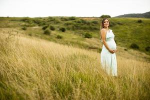 junge schwangere Frau, die draußen in der Natur entspannt foto