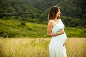 junge schwangere Frau, die draußen in der Natur entspannt foto