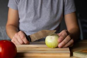 Herren Hände Schnitt Zwiebeln auf ein hölzern Tafel foto