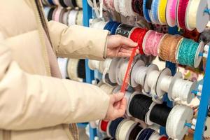 Damen Hände wählen ein rot Band von mehrfarbig Bänder im ein Kunst Geschäft foto