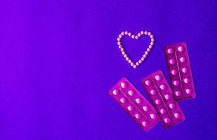 Herz Symbol gemacht von Tabletten und Tablets Blase auf ein Blau Hintergrund mit Kopieren Raum. Empfängnisverhütung und Damen Gesundheit Konzept. kreativ Idee zum online Apotheke und pharmazeutische Unternehmen Geschäft. foto