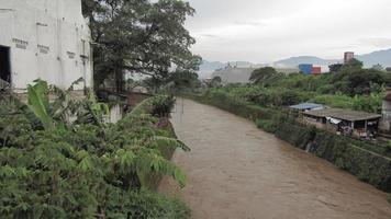 schlammig Fluss im das Stadt mit Dorfbewohner Haus auf das Seite mit groß Bäume foto