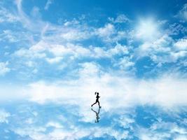 3d Silhouette einer Frau, die gegen einen Himmel joggt, der im Boden reflektiert wird foto