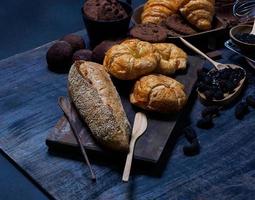 Draufsicht frisches Brot braune Rosinen Sesambäckerei aus Weizenmehl Lebensmittel hausgemacht geeignet für gesunde Ernährung auf Holztischboden schwarzer rustikaler dunkler Hintergrund foto