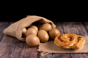 Croissant und Eier in einem Leinensack auf Holztisch
