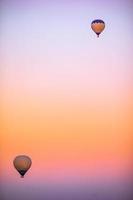 Heißluftballon fliegt über felsige Landschaften in Kappadokien mit schönem Himmel im Hintergrund foto