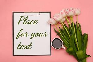 Text Platz zum Ihre Text, Nächster zu ein Strauß von zart Rosa Tulpen und mit ein Tasse von Kaffee auf ein Rosa Hintergrund. Dort kann Sein Ihre Text foto