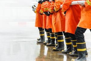 Feuerwehrleute mit Feuerlöscher und Wasser aus dem Schlauch foto