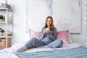 attraktiv Brünette Frau ist Sitzung auf Bett im ihr Pyjama Trinken heiß Tee oder foto