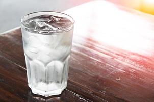 Glas Wasser mit Eis auf Holztisch, sauberes Wasser, Trinkwasser foto