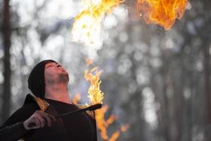 das Mann hat Feuer und Rauch Kommen aus von seine Mund. Feuershow.jung Mann weht Feuer von seine Mund foto