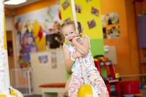 ein wenig Mädchen Fahrten ein Seil im ein Kinder- Center. foto