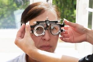 ein Augenarzt wählt aus Brille zum ein Frau mit ein einstellen von Versuch Schauspiel Linsen. ein geduldig beim ein Augenarzt Termin. foto