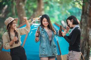 junge frauen jubeln und trinken getränke vor dem campingzelt foto