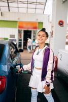 Frau, die ihr Auto an einer Tankstelle mit Kraftstoff befüllt foto