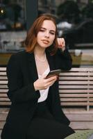 junge Frau benutzt das Telefon im Straßencafé foto