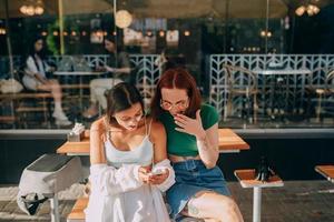 mädchen, die smartphones benutzen, während sie draußen im café sitzen foto