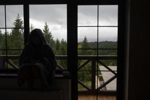 Frau sitzt auf der Fensterbank und schaut auf die Berge foto