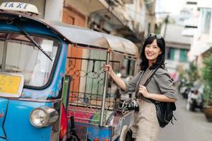 jung asiatisch Frau Rucksack Reisender Stehen ein Seite von Tuk Tuk Taxi auf Sommer- Urlaube beim Bangkok, Thailand. foto