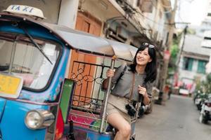 jung asiatisch Frau Rucksack Reisender Stehen ein Seite von Tuk Tuk Taxi auf Sommer- Urlaube beim Bangkok, Thailand. foto