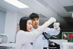 Zwei junge medizinische Wissenschaftler, die Reagenzgläser im medizinischen Labor betrachten, wählen den Fokus auf männliche Wissenschaftler foto