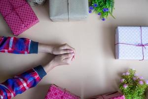 das Mädchen Hand mit das Geschenk Box platziert auf das Tisch. glücklich Zeit Konzept foto