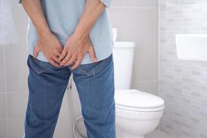 asiatisch Mann leidet von Durchfall in der Nähe von ein Toilette Schüssel haben Bauch Magenschmerzen ,Verstopfung im Badezimmer krank Menschen Hand von das Bauch Durchfall Bauch Gesundheit Problem. foto