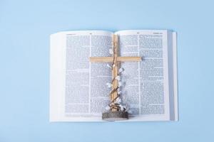 öffnen heilig Bibel mit Kreuz und dekorativ Blumen auf Blau Hintergrund foto