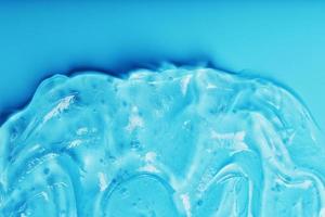 Gel mit hyaluronic Acid im das bilden von ein Abstrich von glänzend Textur auf ein Blau Hintergrund. foto