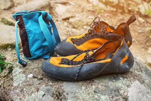 Orange Klettern Schuhe und Magnesium im ein Blau Tasche Stand auf ein Stein. Klettern Kleidung foto