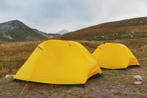 zwei Gelb Zelt auf ein Hintergrund von ein Senke mit Berge im Herbst foto