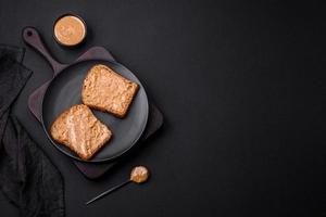 nahrhaft Sandwich bestehend aus von Brot und Erdnuss Butter auf ein schwarz Keramik Teller foto