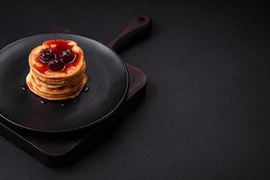 köstlich frisch Pfannkuchen mit Beere Marmelade auf ein schwarz Keramik Teller foto