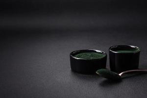 würzen, Grün Farbe Spirulina im das bilden von Pulver im ein schwarz Schüssel foto