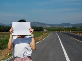 jung asiatisch Frau halten ein Vorderseite Buchseite. auf das Straße. Werbetafel. Weiß Raum zum Ihre Kopieren. foto