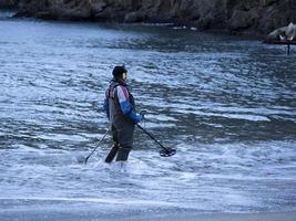 Mann sucht mit Metalldetektor am Strand foto