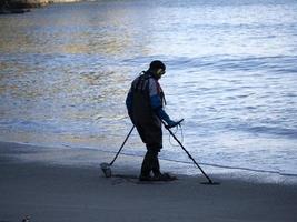 Mann sucht mit Metalldetektor am Strand foto