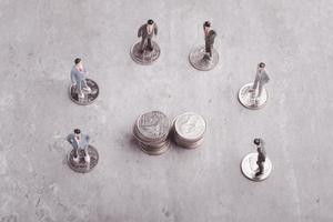 Miniatur Menschen Stehen um Münzen, Geschäft Mann zittern Hände während ein treffen, Erfolg, Umgang, Gruß und Partner Konzept. foto