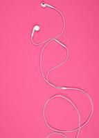 Kopfhörer mit ein Weiß Kabel auf ein Rosa Hintergrund foto